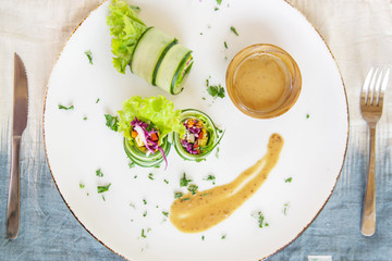Thinly sliced raw zucchini rolls with veggies and peanut sauce, organic vegetarian healthy snack	