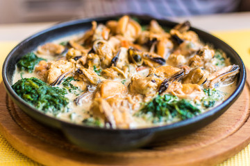 Mussels in a creamy spinach sauce in a pan.