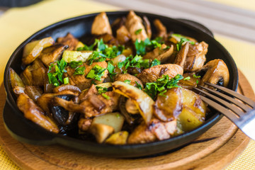 Potatoes with vegetables and meat, sprinkled with herbs and spices in a pan.
