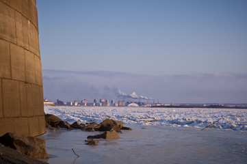 The frozen river. Embankment on the left. River debris and rocks frozen in the ice