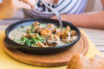 Mussels in a creamy spinach sauce in a pan.