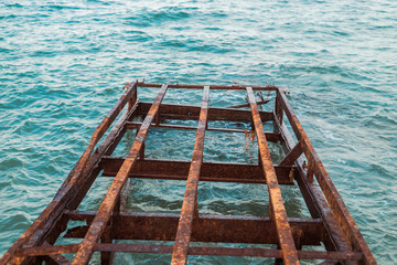 Rusty ruined pier on the sea. Iron structures corroded in water.