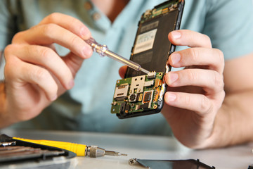 Technician repairing mobile phone at table, closeup