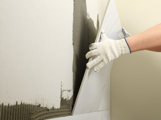 Worker installing ceramic tile on wall, closeup. Space for text