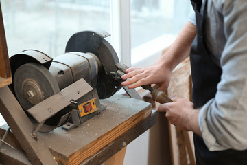 Working man using grinding machine at carpentry shop, closeup