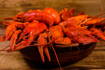 Plate with boiled crayfishes on wooden table
