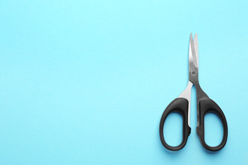 Pair of sharp scissors on color background, top view. Space for text