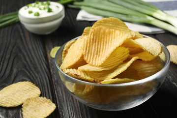Bowl with potato chips on wooden table, closeup. Space for text
