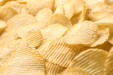 Pile of crispy potato chips as background, closeup