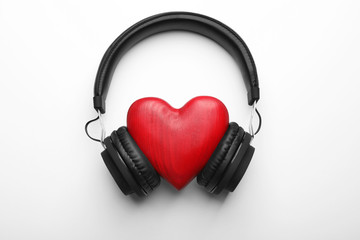 Fototapeta na wymiar Decorative heart and modern headphones on white background, top view