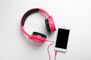 Stylish headphones and modern phone on white background, top view. Space for text