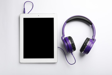 Stylish headphones and modern tablet on white background, top view. Space for text