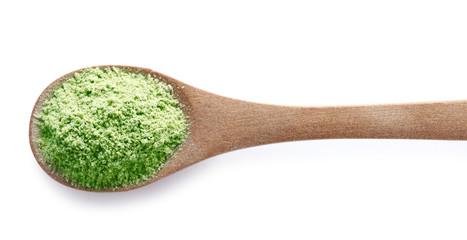 Wheat grass powder in wooden spoon on white background, top view