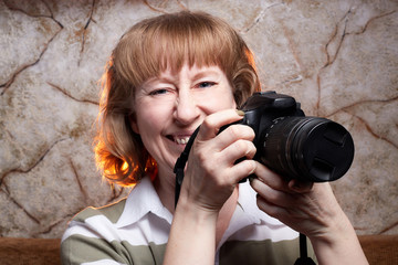 Blonde-haired female photographer with photo camera in her hands