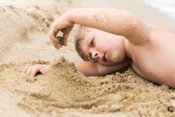 A little boy builds from sand on the seashore, the ocean. Baby is played on the beach.