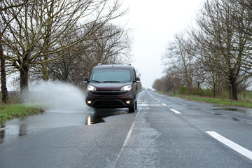 Wet suburban road with car on rainy day