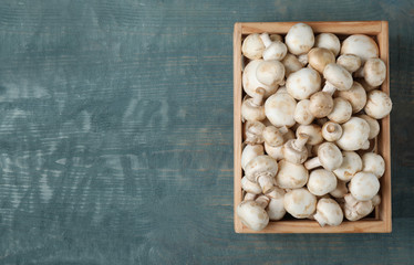 Wooden crate full of fresh raw mushrooms on table, top view. Space for text