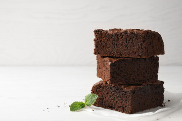 Parchment paper with fresh brownies on table against light background, space for text. Delicious chocolate pie