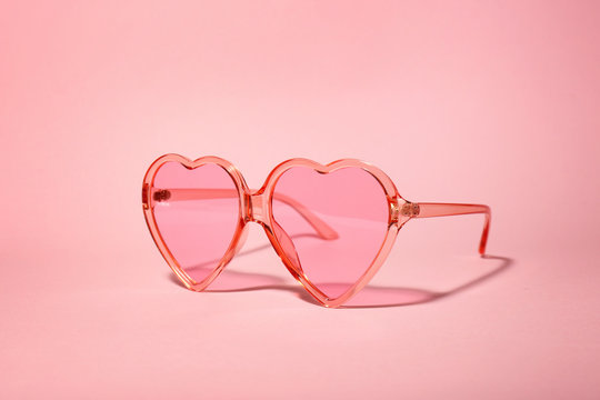 Stylish heart shaped glasses on color background