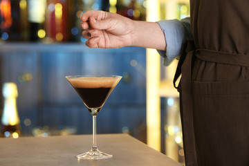 Woman preparing Espresso Martini on bar counter, closeup. Alcohol cocktail