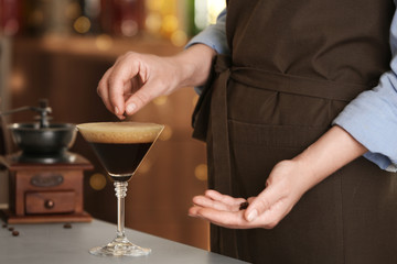 Woman preparing Espresso Martini on bar counter, closeup. Alcohol cocktail