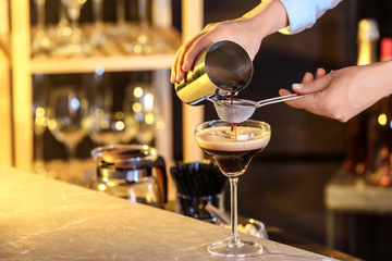 Woman preparing Espresso Martini on bar counter, closeup. Alcohol cocktail