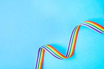 Bright rainbow ribbon on color background, top view with space for text. Symbol of gay community