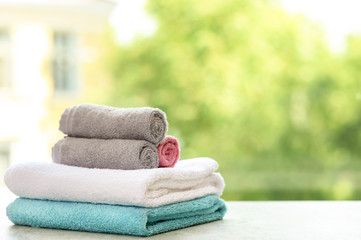 Stack of clean towels on table against blurred background. Space for text