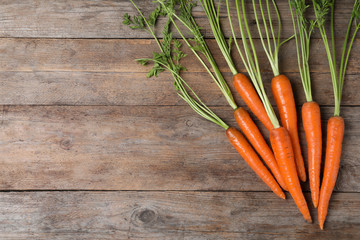 Flat lay composition with carrots on wooden background. Space for text