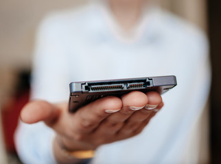 Woman presenting demonstrating holding in palm new small fast SSD 4tb 10tb computer disk drive with SATA connectivity