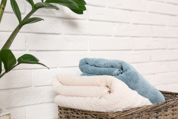 Fototapeta na wymiar Basket with clean folded towels near brick wall