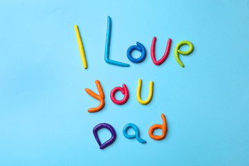 Phrase I LOVE YOU DAD made of plasticine on color background, top view