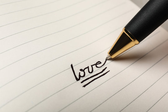 Writing word LOVE in journal, closeup view