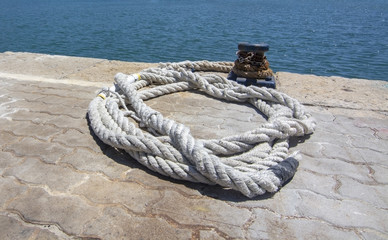 Fototapeta na wymiar Thick white mooring rope closeup on empty mooring place