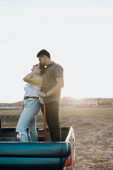 Fototapeta premium Beautiful Young couple kissing on top of jeep 4x4 car on sunset