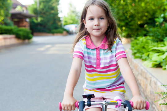 Children learning to drive a bicycle on a driveway outside. Little girls riding bikes on asphalt road in the city. . Active healthy outdoor sports for young children. Fun activity for the baby concept © tgordievskaya