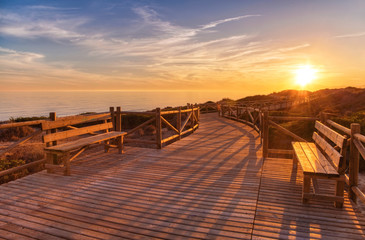 Weathered lumber path leading to calm sea during beautiful sunset