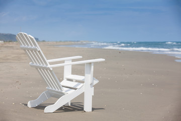 Empty white wooden chair at a paradisiac beach on the tropics in a beautiful sunny day