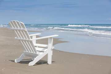 Empty white wooden chair at a paradisiac beach on the tropics in a beautiful sunny day