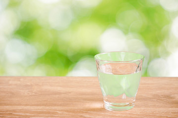 Glass of water on the table. Nature background.  テーブルの上にあるグラス一杯の水と自然背景