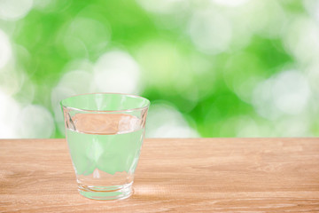 Glass of water on the table. Nature background.  テーブルの上にあるグラス一杯の水と自然背景