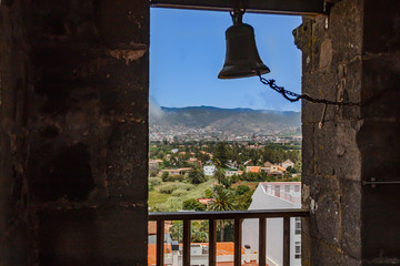 Obraz premium View through the window of church tower of the historic town of San Cristobal de La Laguna in Tenerife showing the buildings and streets with mountains in the background
