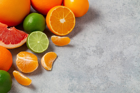 group of whole and sliced citrus fruits - tangerines, lemons, limes, oranges, grapefruits on the surface of the gray table - image with copy space © Галина Сандалова