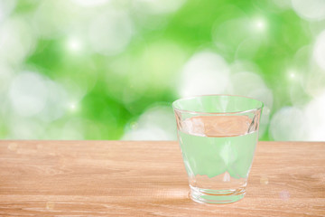 Glass of water on the table. Nature background.  Backlight addition version. テーブルの上にあるグラス一杯の水と自然背景。逆光追加版