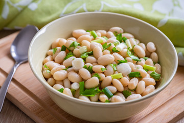 White bean salad with green onion in bowl.