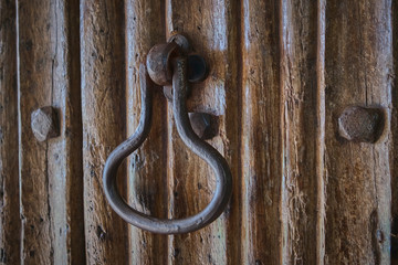 Old iron door knocker on a wooden door