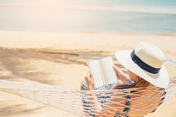 Woman reading a book on hammock beach in free time summer holiday