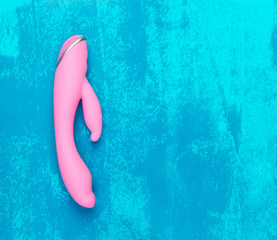 A charming evenly lit pink dildo on a dirty blue background with copy space.