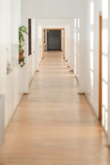 Long empty hallway inside an old building with white freshly painted walls and parquet floors