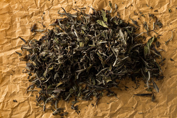 Dried, raw white tea leaves on brown packing paper background top view flat lay from above
